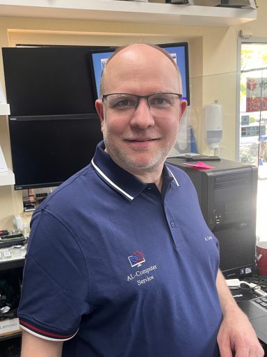 A. Lorentz - Techniker Mann mit Brille in einem Geschäft, trägt ein blaues Polohemd und lächelt.